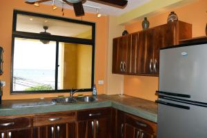 a kitchen with a refrigerator and a sink and a window at Beachfront Condo El Torreón San Juan del Sur in San Juan del Sur