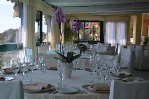 a dining table with glasses and a vase with flowers at Hotel & Spa Villa del Mare - Adult Only in Maratea