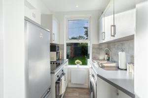 eine weiße Küche mit einem Waschbecken und einem Fenster in der Unterkunft Beautiful Ground Floor Apartment in Perth