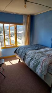 1 dormitorio con 1 cama con pared azul y ventana en Pies a tierra, en Coyhaique