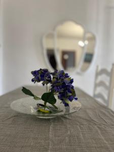 a vase with purple flowers on a plate on a table at Casa LuLa in Villafranca de Córdoba
