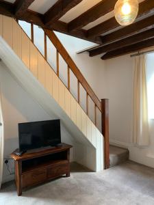 een woonkamer met een tv en een trap bij Bwthyn Bach Gilfach in Bangor