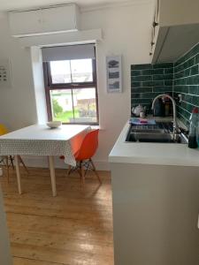 a kitchen with a table and a sink and a table and a window at Bwthyn Bach Gilfach in Bangor