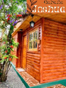 un pequeño edificio de madera con una puerta y flores en Cabaña Joshua en Puerto Iguazú