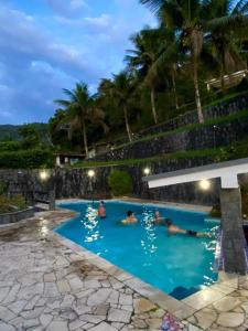 Un grupo de personas en una piscina por la noche. en Casa da Uba Una, en Ubatuba