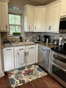 una cocina con armarios blancos y una alfombra en el suelo en Milton-Quite, Country Coastal Cottage-Ocean vibes, en Milton