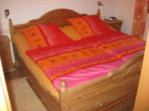 サシュラングにあるFerienhaus Sachrangの木製ベッド(オレンジ、赤のシーツ、枕付)