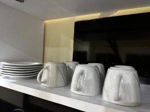 uma fila de vasos brancos numa prateleira com placas em Apartamentos Sin fronteras em Letícia