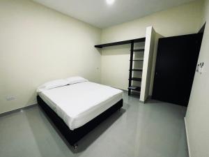 a bedroom with a white bed and a book shelf at Apartamentos Sin fronteras in Leticia