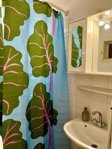 a bathroom with a shower curtain with leaves on it at Cosy Art Flat 2 in Budapest