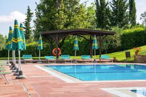 uma piscina com um gazebo, cadeiras e guarda-sóis em Borgo Collelungo apartments in Montaione em La Collina