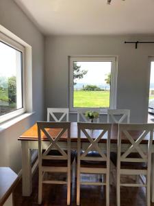 a dining room with a table and chairs and two windows at Harbour View Cottage, Rochespoint, Cork Harbour in Midleton