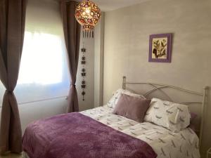 um quarto com uma cama com um lustre e uma janela em El Portil, Punta Umbría. A 300m playa. Piscina em El Portil