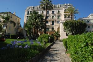 ein Gebäude mit Palmen und lila Blumen davor in der Unterkunft Giardino del Mare in Bordighera