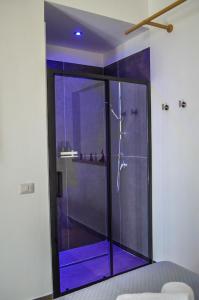 Eine Glasdusche in einem Badezimmer mit violetter Beleuchtung in der Unterkunft Scavi 32 in Ercolano