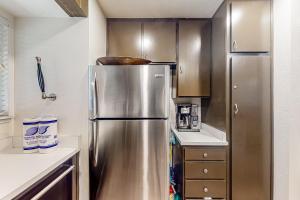 um frigorífico de aço inoxidável numa cozinha com armários de madeira em Huntington Lake Condo #102 em Lakeshore