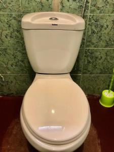 a white toilet in a bathroom with a green wall at Nomads nest safari house in Arusha