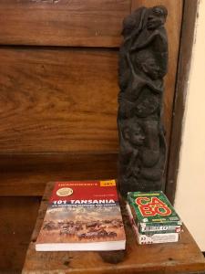 zwei Bücher auf einem Tisch neben einer Statue in der Unterkunft Nomads nest safari house in Arusha