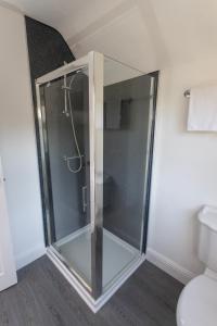 a glass shower in a bathroom with a toilet at Pinfold Cottage York in York