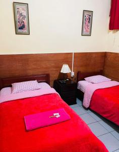 Cette chambre comprend 2 lits avec une couverture rouge. dans l'établissement KORICANCHA, à Lima