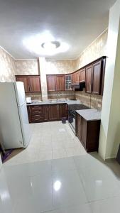 an empty kitchen with wooden cabinets and a refrigerator at Sara apartment in Wadi Musa
