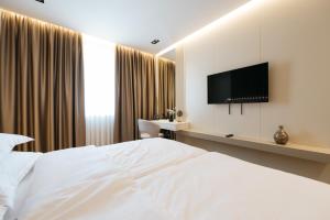 a bedroom with a white bed and a flat screen tv at Hotel Kod Barića in Grude