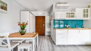 een keuken met witte kasten en een tafel met een vaas met bloemen bij BALTIC PARK A Apartamenty PIAMOLA in Stegna