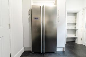 a stainless steel refrigerator in a kitchen with white cabinets at NEWLY REFURBISHED House - FREE Wi-Fi! in Wyken