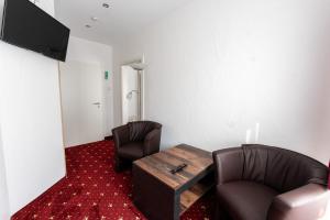 Zimmer mit 2 Stühlen, einem Tisch und einem TV in der Unterkunft Hotel Haus Biggen in Attendorn