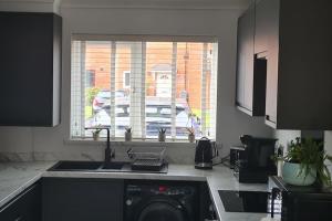 a kitchen with a sink and a dishwasher and a window at Runway Airbnb in Manchester
