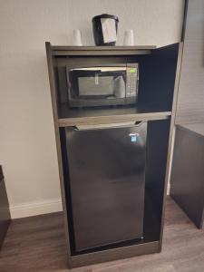 a microwave sitting on top of a stand with a refrigerator at Motel 6 Sacramento CA Natomas in Sacramento