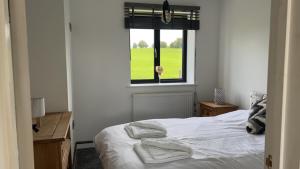 a bedroom with a bed with white sheets and a window at Immaculate 3-Bed Barn in Uttoxeter in Uttoxeter