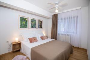 a white bedroom with a large bed and a ceiling fan at Villa Beller New in Ičići
