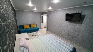 - une chambre avec un canapé bleu et une télévision murale dans l'établissement Однокомнатная квартира в центре Петропавловска, à Petropavlovsk-Kamtchatski