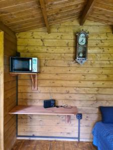 a room with a microwave and a clock on a wall at Trekkershut in Wallenborn