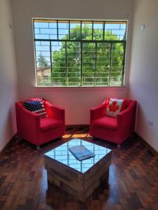 uma sala de estar com duas cadeiras vermelhas e uma mesa de centro em Hostel Kaizen em Curitiba
