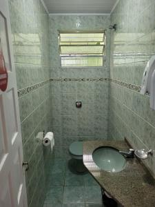 ein Badezimmer mit grünem WC und Waschbecken in der Unterkunft Hostel Kaizen in Curitiba