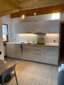 a kitchen with white cabinets and a wooden floor at Obereggen - Anna in Eggen