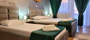 two beds in a hotel room with green curtains at Cabana Mea STRAJA in Lupeni +39 photos