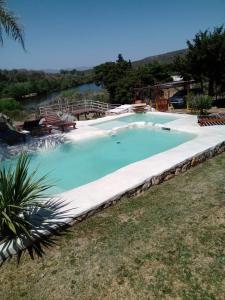 a large swimming pool with a river in the background at Las Acacias Refugio in La Falda