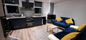 a living room with a blue couch and a kitchen at Sapphire Strathnairn Apartment in Cardiff