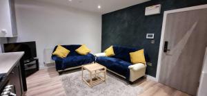a living room with two blue couches with yellow pillows at Sapphire Strathnairn Apartment in Cardiff