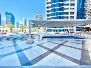 a pool with a white umbrella and chairs and buildings at Seaside, renewed poshy apartment on JBR in Dubai