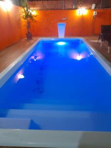 a swimming pool with blue lights in a room at Aconchego in Guarujá