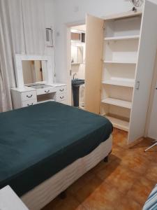 um quarto com uma cama, um espelho e prateleiras em Aconchego no Guarujá