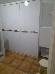 a room with white cabinets and a table and a stool at Aconchego in Guarujá
