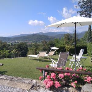 ein paar Stühle, ein Regenschirm und Blumen in der Unterkunft Casa Via Castelmonte in Cividale del Friuli