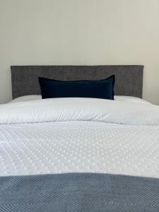 Una cama blanca con una almohada azul. en A Village Gem en Mullingar