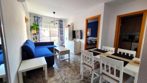 Una sala de estar con un sofá azul y un comedor. en Apartament Silvia, en Torrevieja