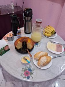 a table with plates of food and a jug of orange juice at POUSADA AMAZONAS in Rio das Ostras